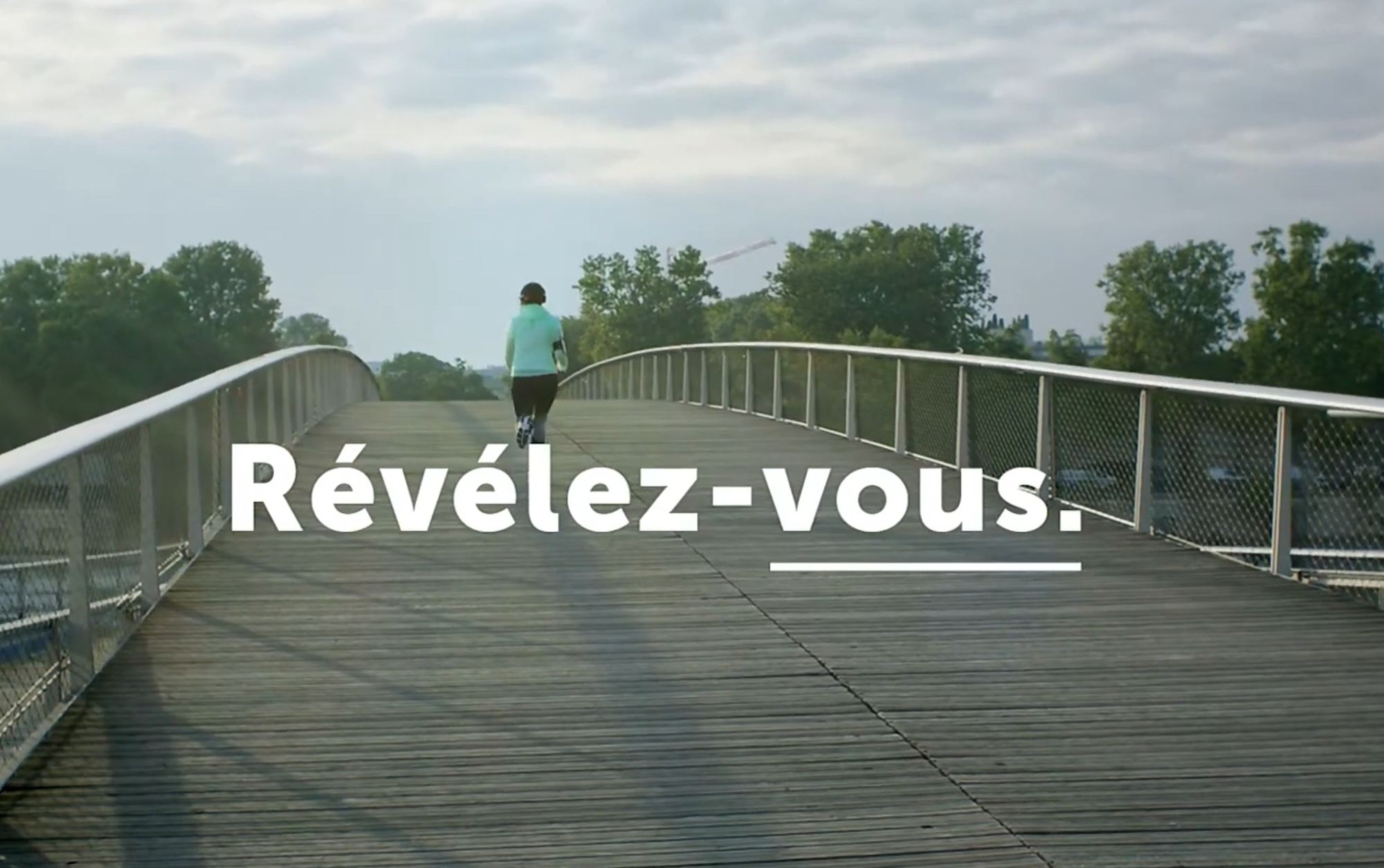 Femme courant sur un pont à l'aube, signature « Révélez-vous » incrustée dans le frame vidéo.